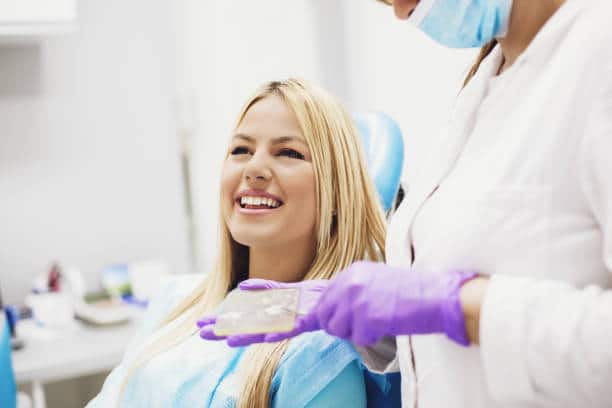 Young blonde woman is sitting in dentist's chair.